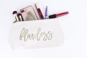 A makeup bag labeled "flawless" with brushes, lipsticks, and a phone sticking out—perfect for OEM ODM customization to suit your brand.
