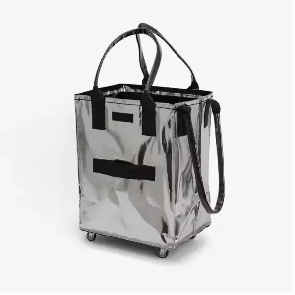 Didelis ratinis PP austi apsipirkimas su užtrauktuku su blizgančiu sidabru, su juodomis rankenomis ir ratais, stovi tiesiai ant balto fono.