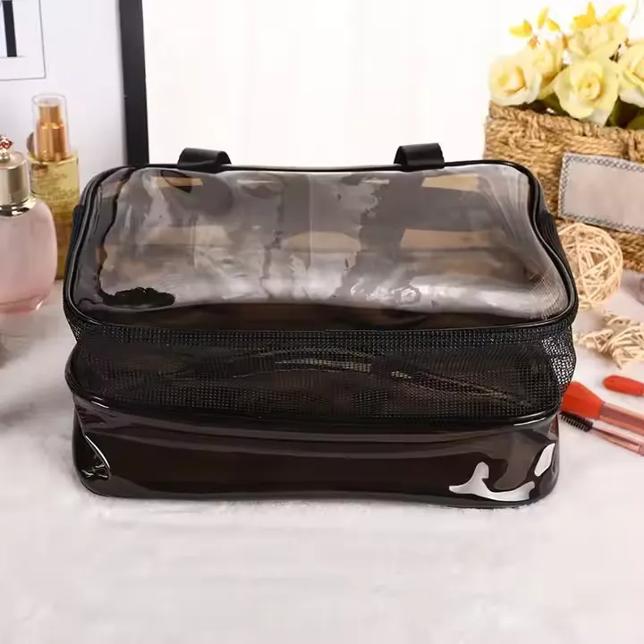 The Black Transparent Toiletry Bag rests on a vanity beside flowers, perfume, and makeup items.
