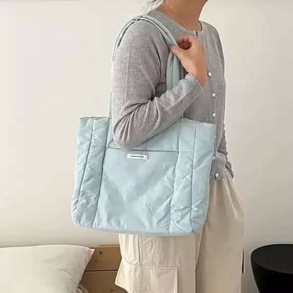 A person wearing a gray cardigan and cream pants carries the Blue Puffed Casual Handbag for Women on their shoulder.
