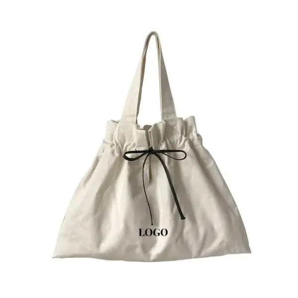 Minimalist Canvas Drawstring Tote for Women in beige with a black ribbon bow and "LOGO" മുൻവശത്ത് അച്ചടിച്ചു. ഒരു ഡ്രോസ്ട്രിംഗ് ടോപ്പ് സവിശേഷതകൾ. ഇഷ്ടാനുസൃത ഒഇഎം, ഒഡിഎം ഓർഡറുകൾ ലഭ്യമാണ്.