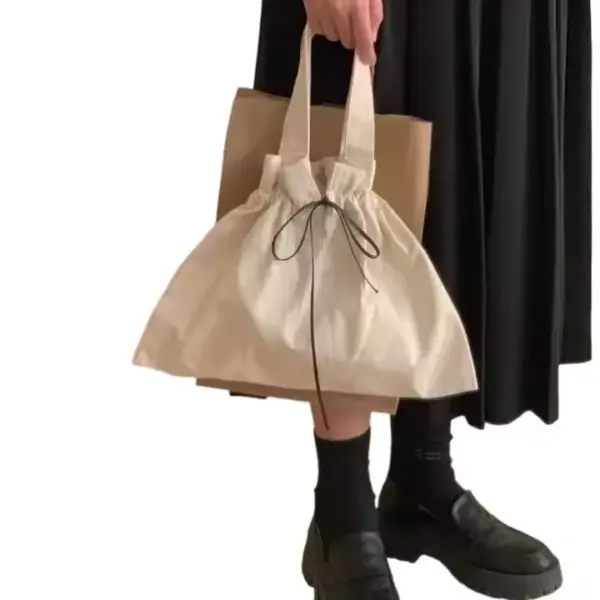 Person in a black skirt holds a Drawstring Canvas Shopping Bag and brown tote, showcasing chic black shoes and socks—ideal for anyone seeking trendy OEM ODM fashion accessories.