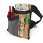 The Electrician/Repairer's Canvas Tool Pouch Belt securely holds gloves, रातो उपकरणहरू, हरियो पेन्सिल, सुरक्षित सुरक्षा चश्मा, र एक टेप मापन.