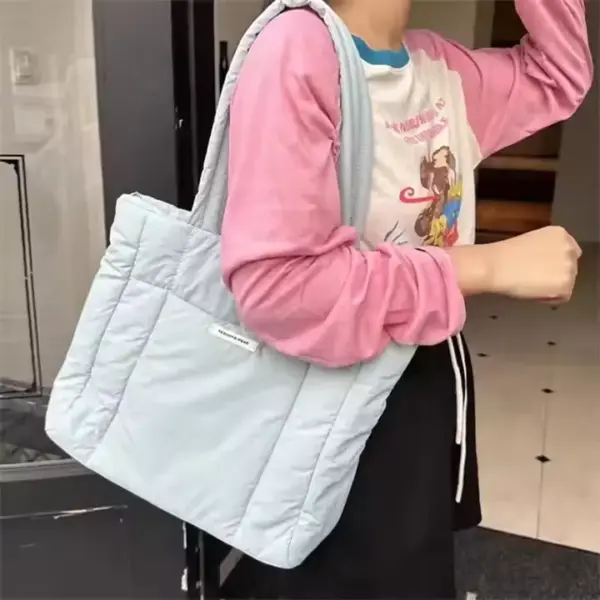 A person wearing a long-sleeved pink and white shirt is carrying the Blue Puffed Casual Handbag for Women, available for OEM and ODM customization.