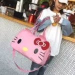 A woman in casual clothes and a white cap stands at a counter holding the Cute Cat-Themed Women's Travel Bag, velik roza duffel, zasnovan za OEM ODM.