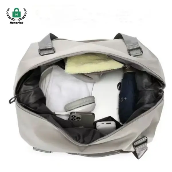 Vista superior de una bolsa de viaje de gran capacidad liviana abierta sosteniendo una toalla, auriculares, teléfono, cargador, y ropa doblada, perfecta para las opciones de personalización ODM OEM.