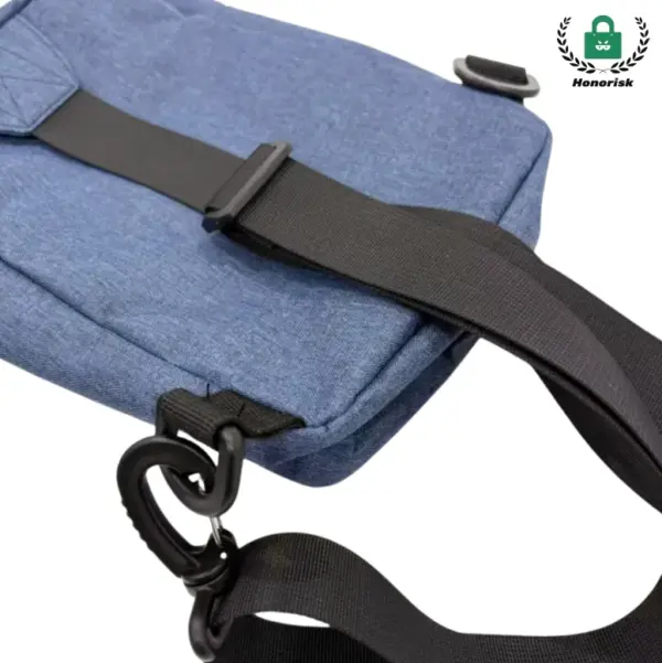 Close-up ta 'pakkett tal-qadd tal-kanvas biż-żippijiet blu / Borża crossbody b'ċinga aġġustabbli sewda u klipp tal-plastik.