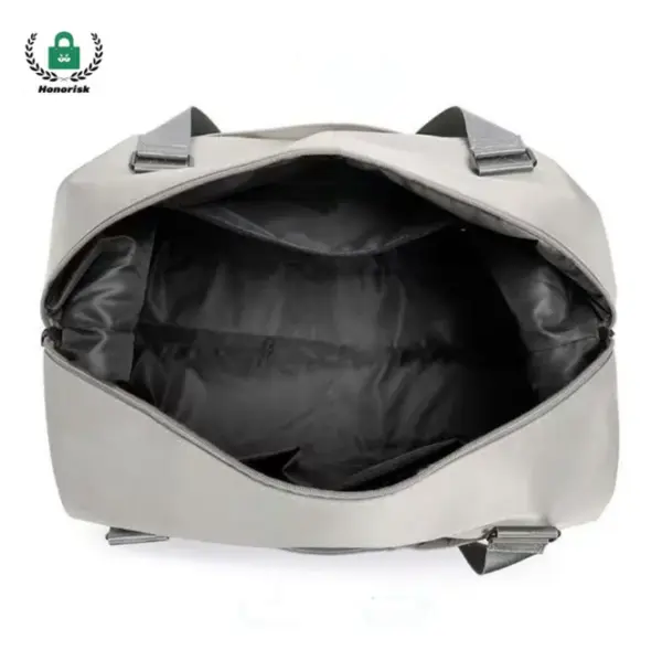 Vista superior de un abierto, bolso de viaje de gran capacidad liviano vacío en gris con interior negro y manijas.