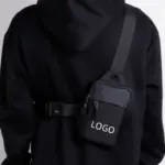 Osoba v černé mikině nosí minimalistický nastavitelný taška Crossbody, featuring "LOGO" Tisk - IDEAL pro přizpůsobení OEM a ODM.